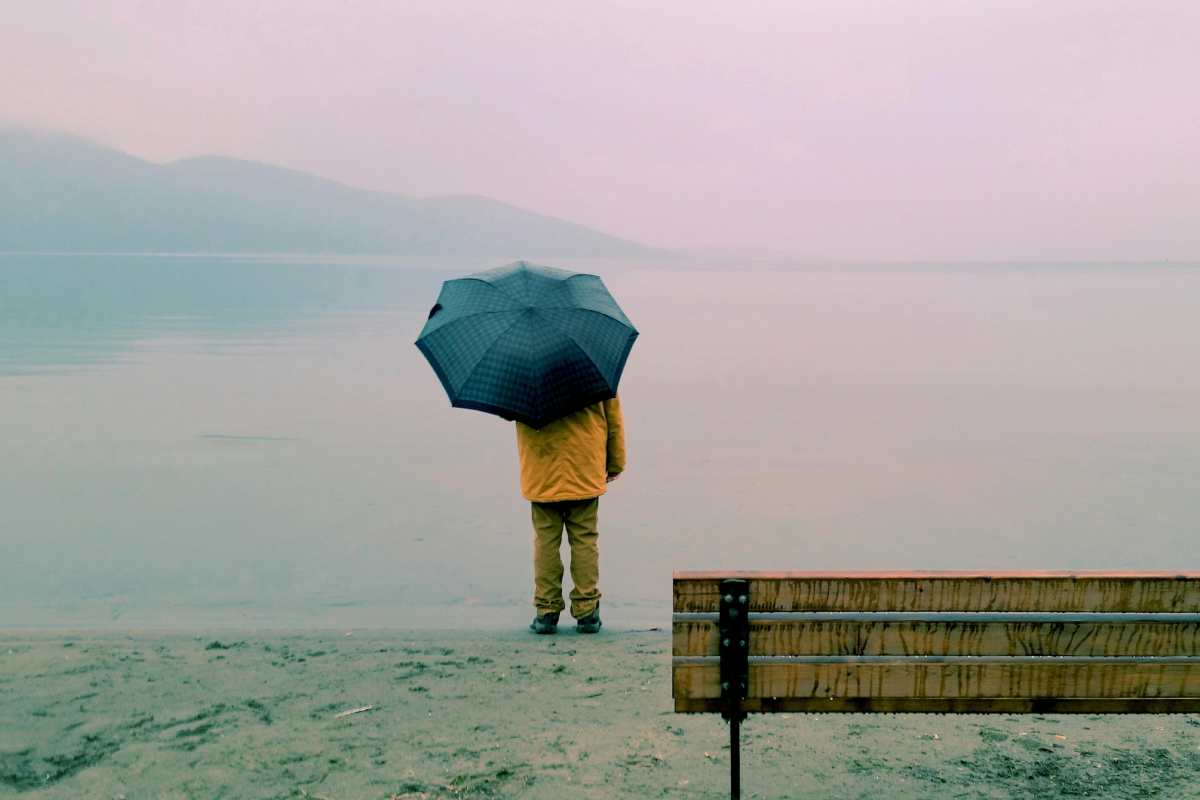 Un uomo con un ombrello sulla sponda di un lago