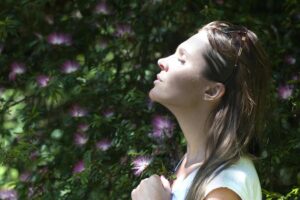 Un volto di donna di profilo e con gli occhi chiusi in un ambiente naturale