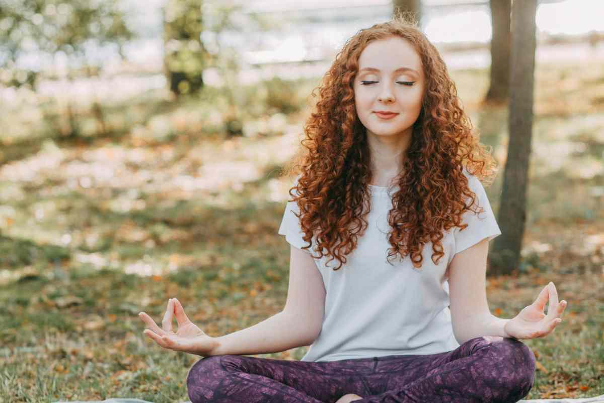Una ragazza con i capelli rossi che fa yoga in un parco