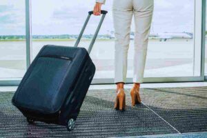 Le gambe di una donna con accanto il suo trolley